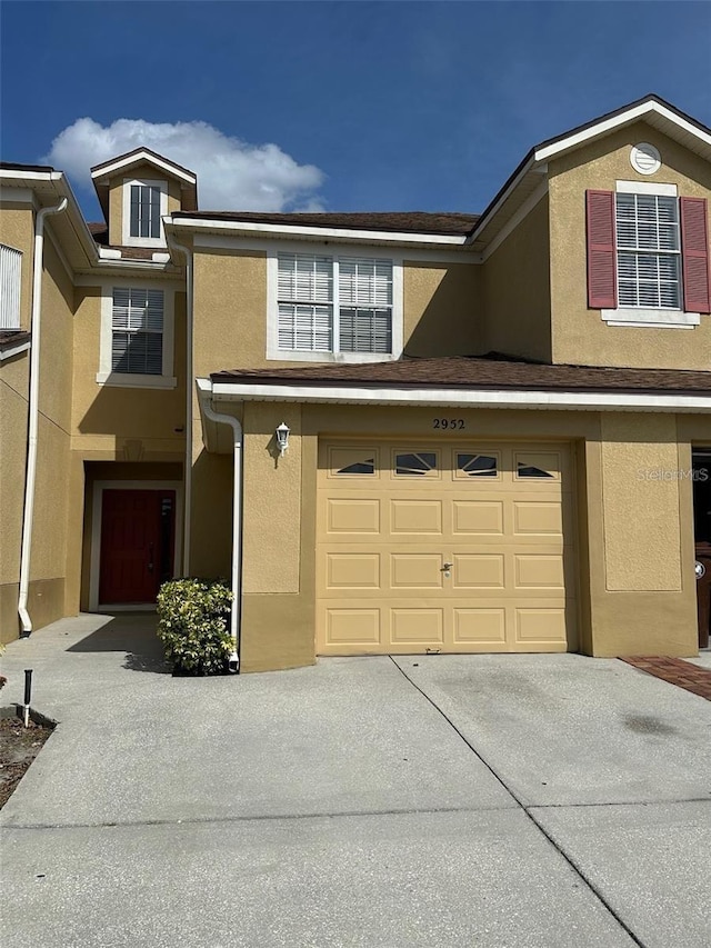 townhome / multi-family property featuring driveway, an attached garage, and stucco siding