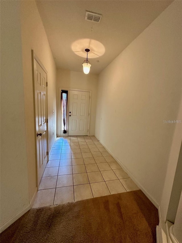 doorway to outside with baseboards, visible vents, and light tile patterned flooring