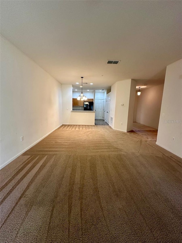 unfurnished living room featuring baseboards, visible vents, and carpet flooring