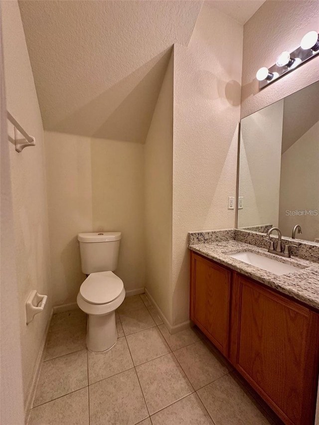 bathroom featuring lofted ceiling, toilet, vanity, a textured ceiling, and tile patterned flooring