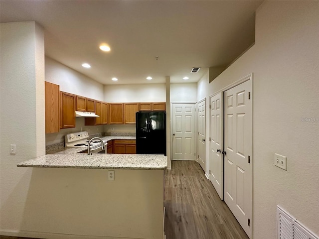 kitchen featuring electric range, visible vents, freestanding refrigerator, a peninsula, and under cabinet range hood