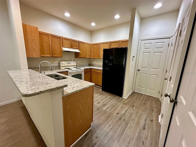 kitchen featuring under cabinet range hood, a peninsula, a sink, black refrigerator with ice dispenser, and white electric range oven