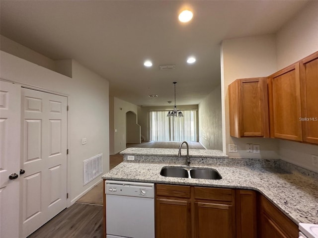 kitchen with visible vents, arched walkways, light stone countertops, white dishwasher, and a sink