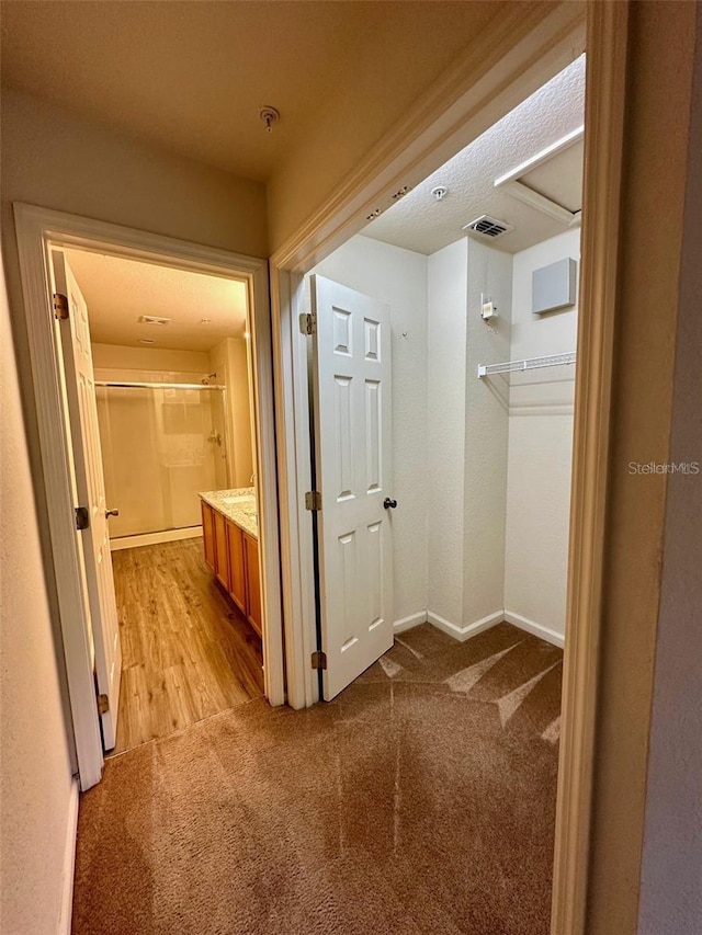 hall featuring baseboards, visible vents, and light colored carpet