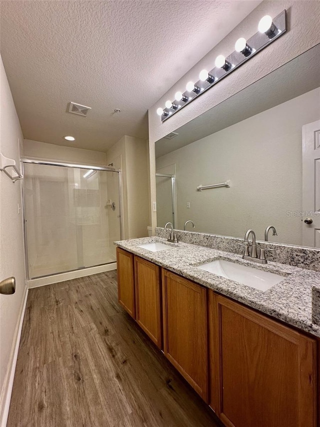 bathroom featuring double vanity, wood finished floors, a sink, and visible vents