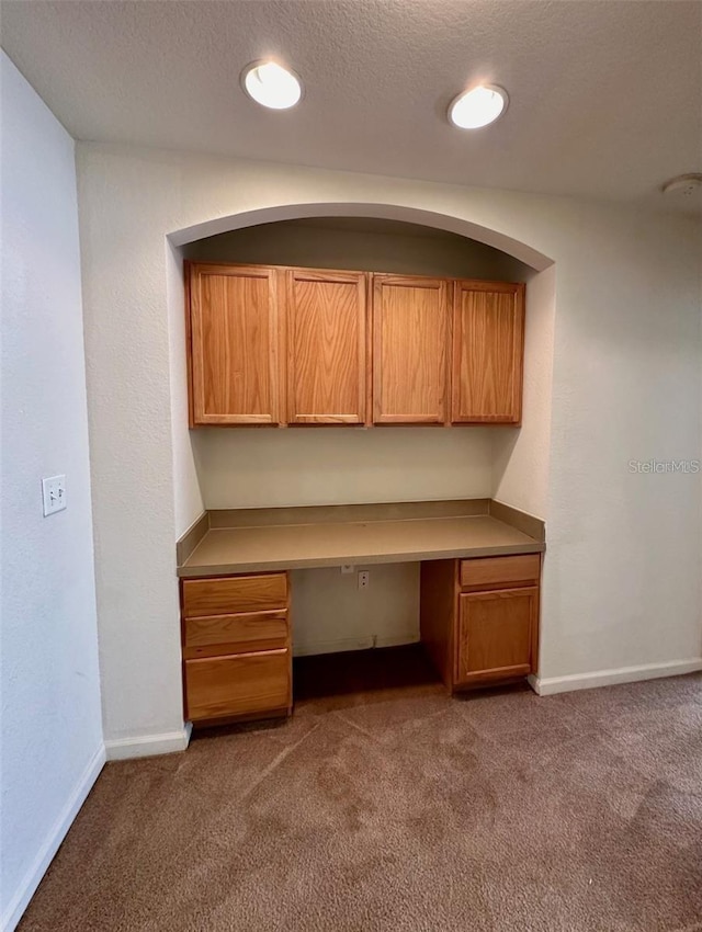 unfurnished office featuring carpet, baseboards, and built in desk