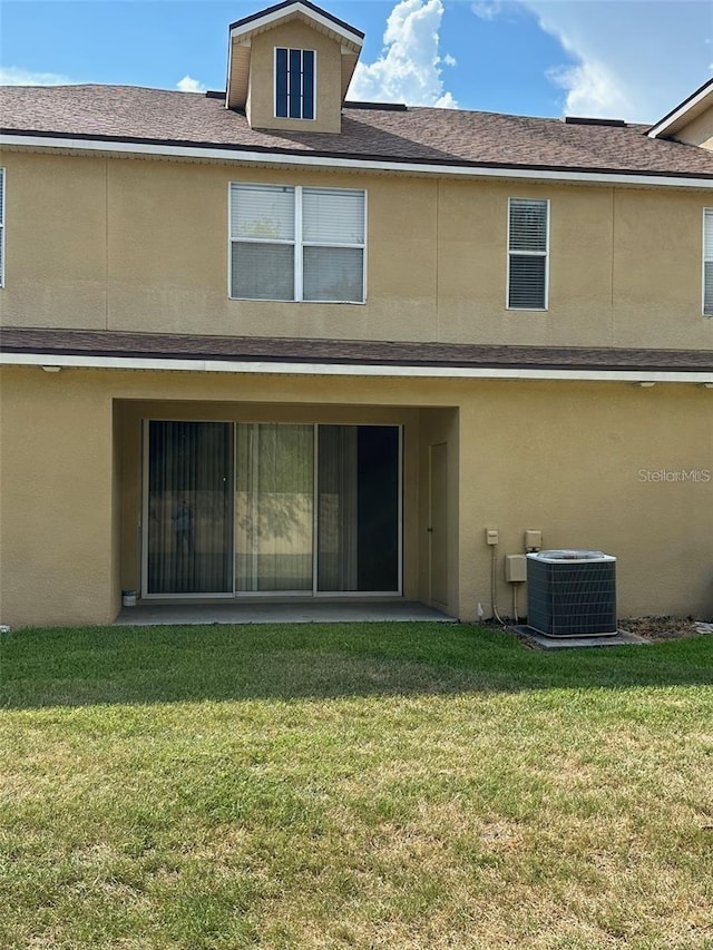 back of property featuring central AC, a yard, and stucco siding