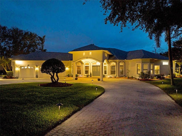 view of front of home with a front yard, curved driveway, and stucco siding