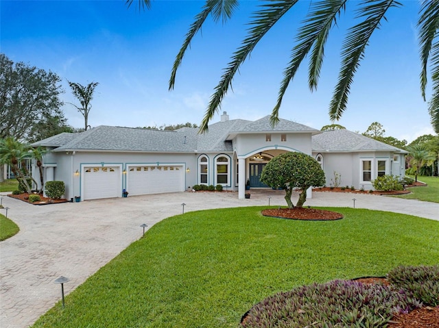 ranch-style home featuring a front lawn, decorative driveway, and stucco siding