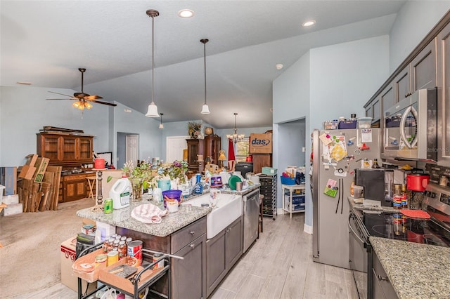 kitchen featuring vaulted ceiling, appliances with stainless steel finishes, decorative light fixtures, and light stone countertops