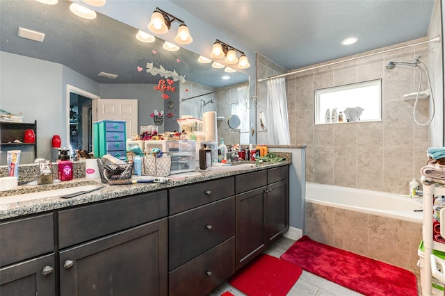 full bathroom with a textured ceiling, tiled shower / bath combo, tile patterned flooring, and vanity