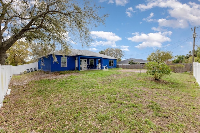 rear view of property with a yard and a fenced backyard