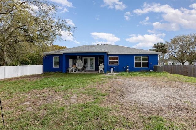 back of property featuring a fenced backyard, a yard, and central AC