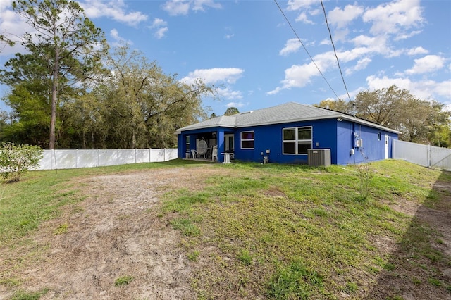 rear view of house with a yard, cooling unit, and a fenced backyard