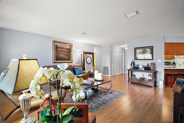 living area featuring visible vents and wood finished floors