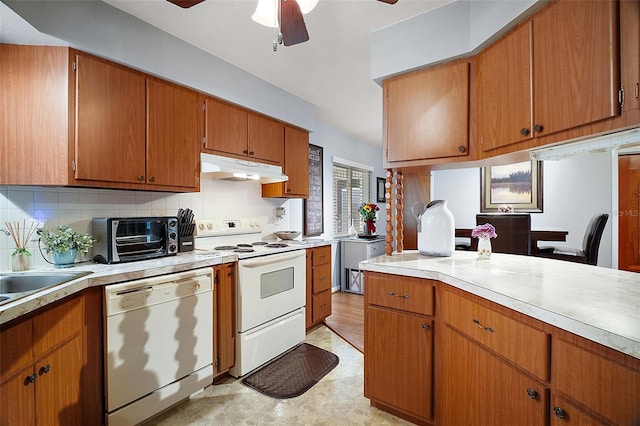 kitchen with light countertops, white appliances, brown cabinetry, and under cabinet range hood