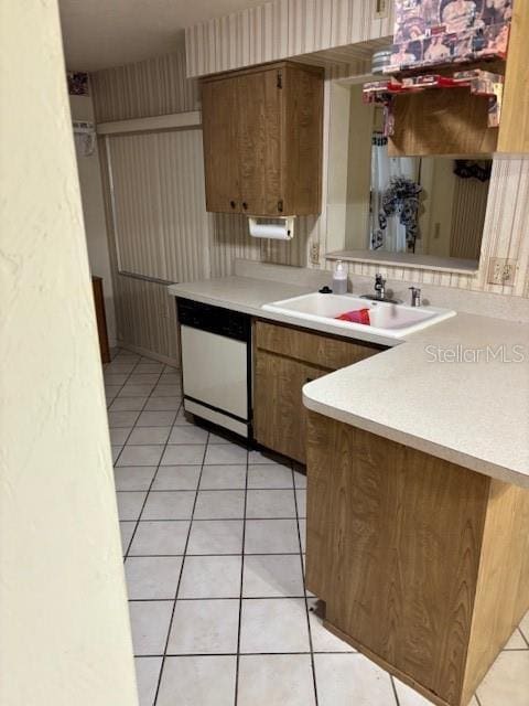 kitchen featuring light tile patterned floors, white dishwasher, a sink, light countertops, and brown cabinetry