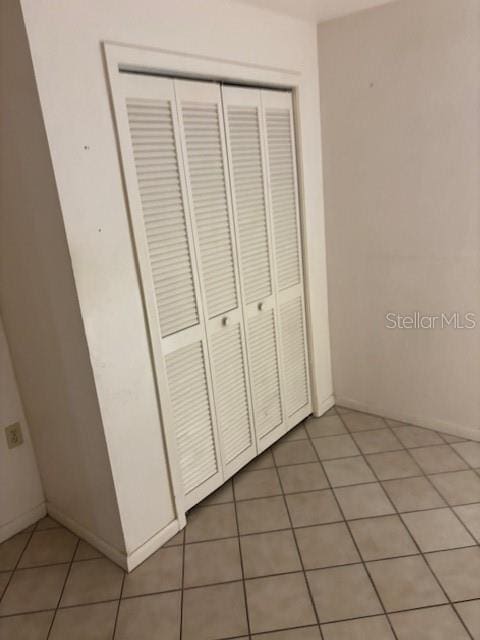 unfurnished bedroom featuring light tile patterned floors and a closet