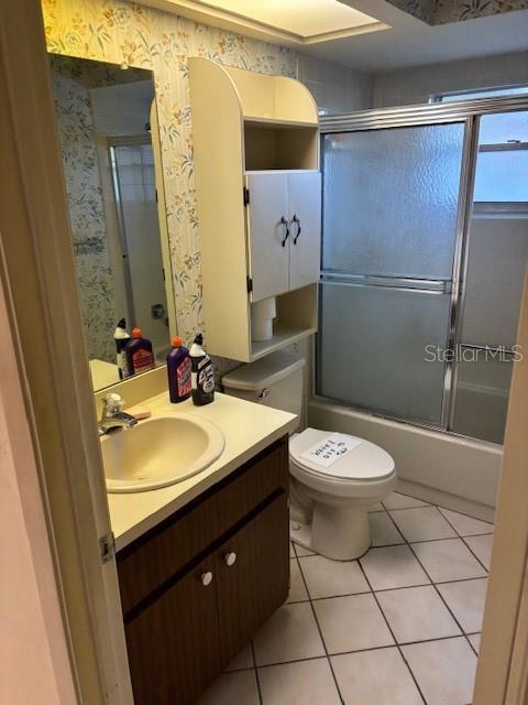 full bath with toilet, enclosed tub / shower combo, vanity, tile patterned flooring, and wallpapered walls