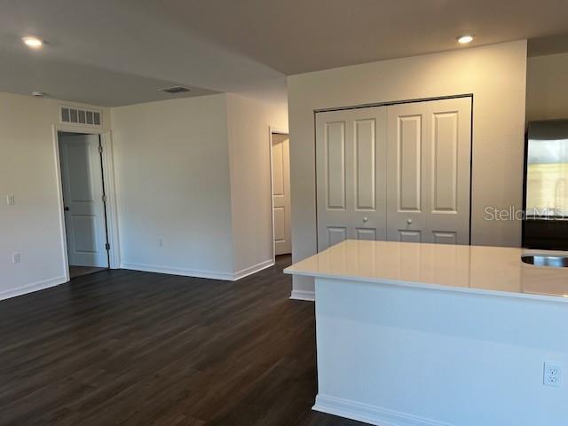 kitchen with dark wood-style floors, recessed lighting, light countertops, visible vents, and baseboards