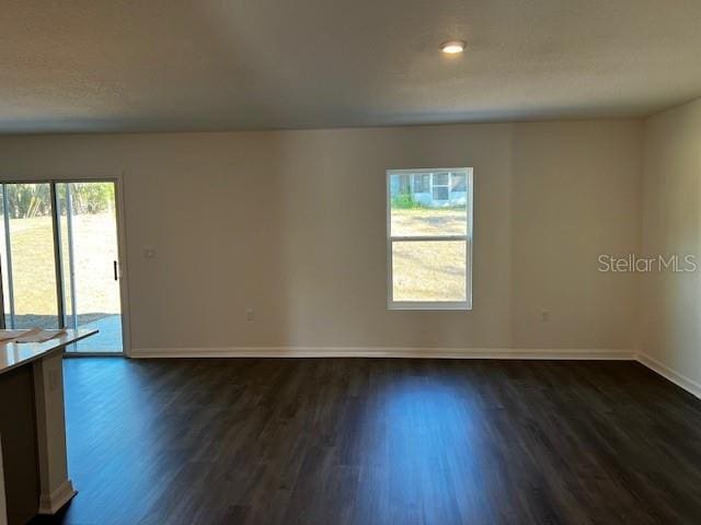 spare room featuring dark wood-style flooring and baseboards