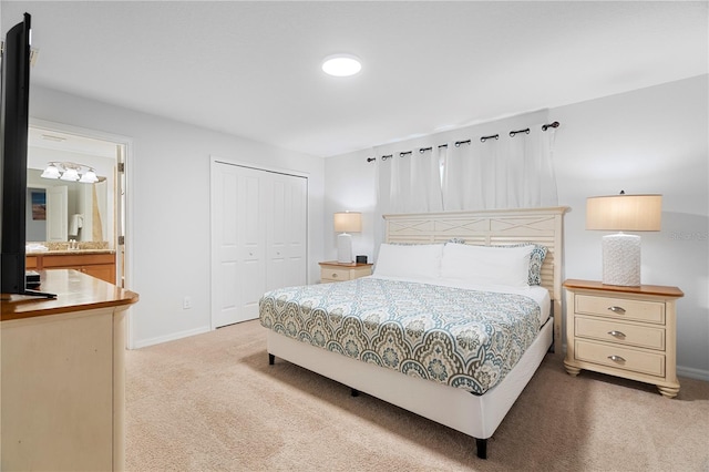 bedroom featuring a closet, light colored carpet, ensuite bath, and baseboards