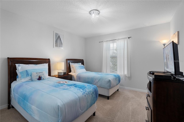 bedroom featuring light carpet, baseboards, and a textured ceiling