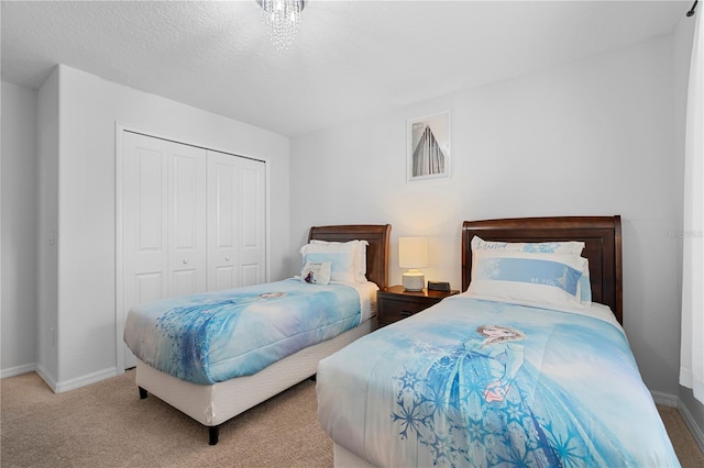 bedroom with a textured ceiling, a closet, baseboards, and carpet flooring