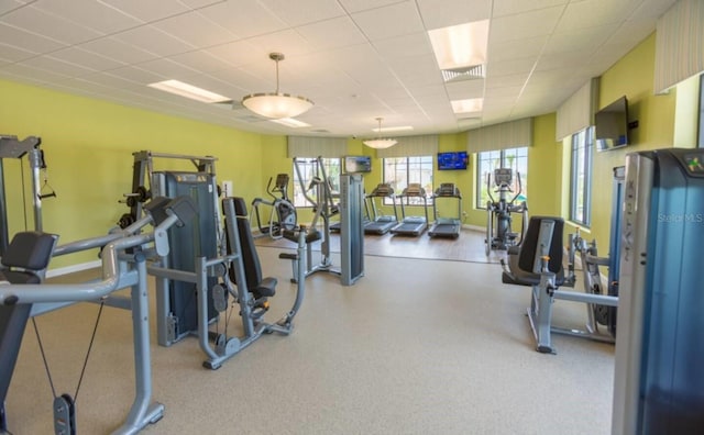 exercise room with a drop ceiling, visible vents, and baseboards