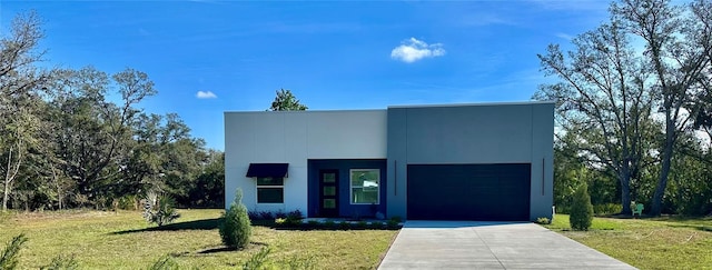 contemporary home with a front yard, concrete driveway, and an attached garage