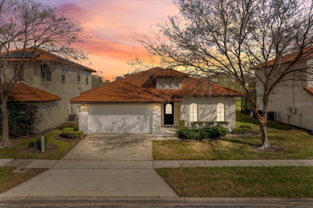 mediterranean / spanish home featuring a tile roof, stucco siding, central AC unit, a garage, and driveway