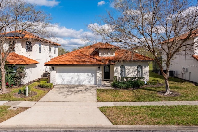 mediterranean / spanish home with a tile roof, stucco siding, concrete driveway, an attached garage, and a front lawn