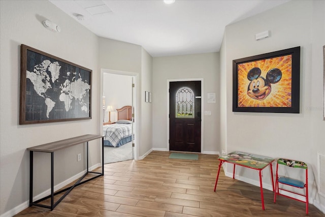 foyer entrance with light wood finished floors, visible vents, and baseboards