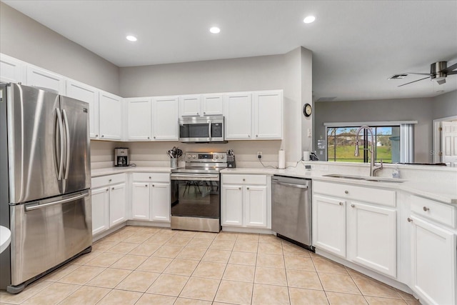 kitchen featuring light tile patterned floors, light countertops, appliances with stainless steel finishes, white cabinets, and a sink