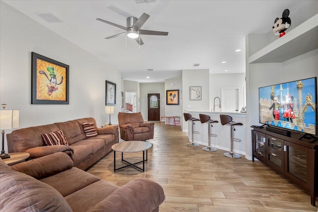 living room with visible vents, baseboards, ceiling fan, light wood-style floors, and recessed lighting