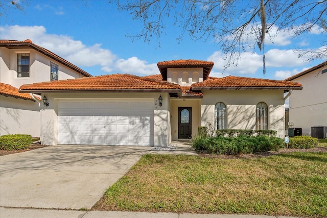 mediterranean / spanish-style house featuring central AC unit, a garage, a tile roof, stucco siding, and a front lawn