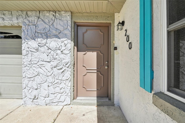 entrance to property featuring a garage and stone siding