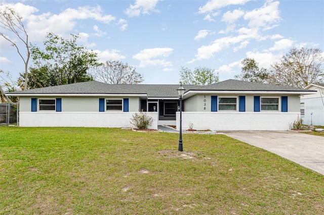 ranch-style home featuring concrete driveway, brick siding, and a front lawn