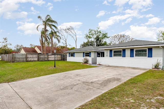 ranch-style home featuring brick siding, stucco siding, fence, and a front yard