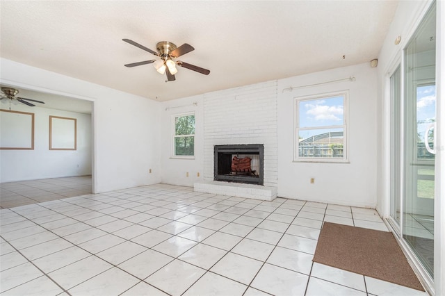 unfurnished living room with ceiling fan, a fireplace, plenty of natural light, and light tile patterned floors