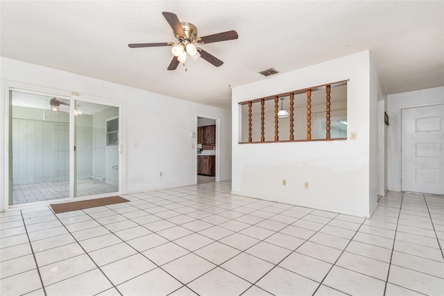 empty room featuring light tile patterned floors, ceiling fan, visible vents, and a textured ceiling