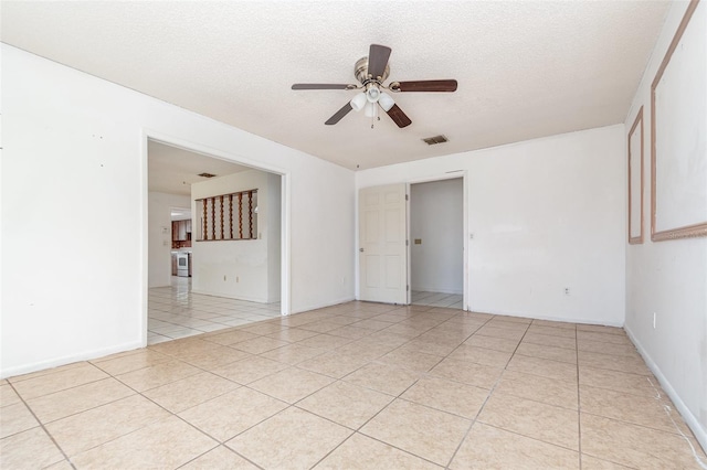 empty room featuring a ceiling fan, visible vents, a textured ceiling, and light tile patterned floors