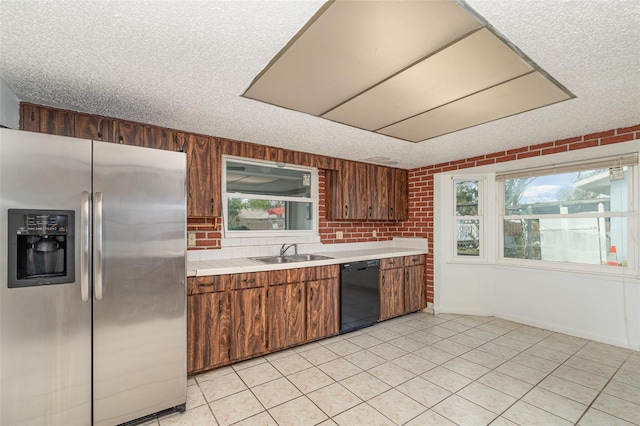 kitchen with a textured ceiling, a sink, light countertops, stainless steel refrigerator with ice dispenser, and dishwasher