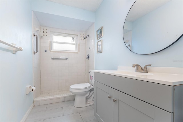 bathroom with tiled shower, vanity, toilet, and tile patterned floors