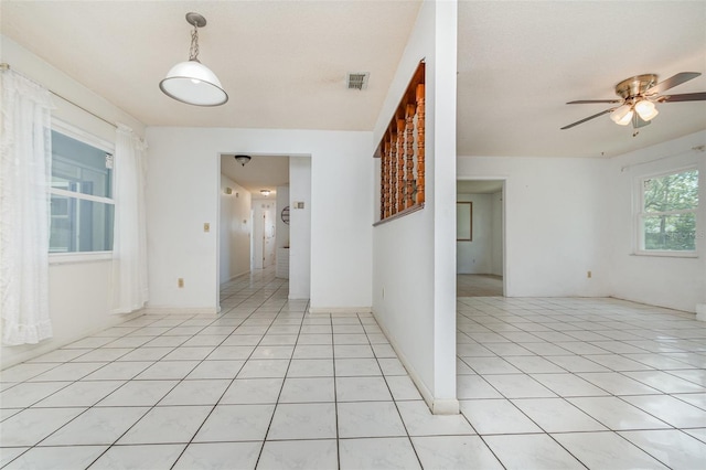 spare room with light tile patterned floors, visible vents, and a ceiling fan