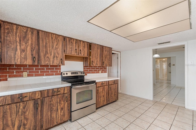 kitchen with stainless steel electric range, visible vents, light tile patterned flooring, a textured ceiling, and baseboards