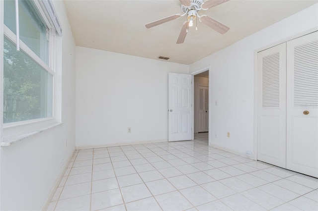 unfurnished bedroom with light tile patterned floors, baseboards, visible vents, a ceiling fan, and a closet