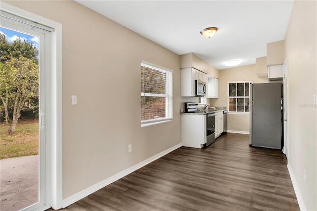 kitchen with dark wood-style floors, appliances with stainless steel finishes, baseboards, and white cabinets