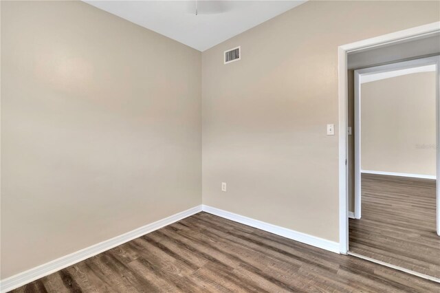 spare room featuring a ceiling fan, visible vents, baseboards, and dark wood-type flooring