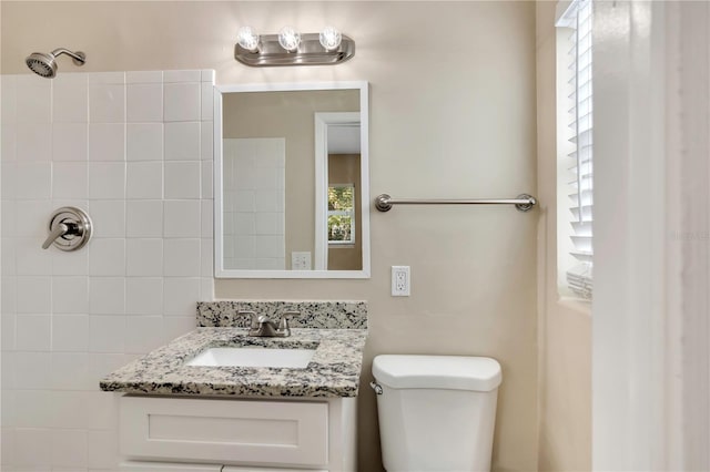 bathroom featuring toilet, a shower, and vanity